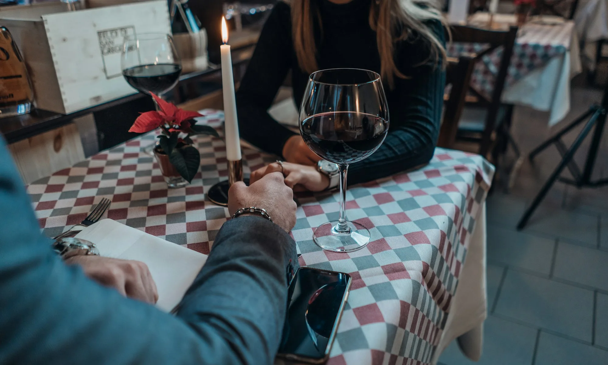 People holding hands over dinner at a small restaurant